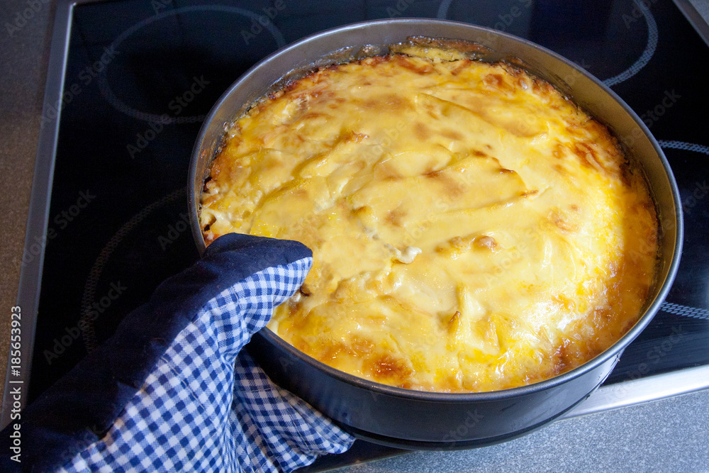 The cook takes from the oven baked fish, hake fillet cooked with carrots, onions, cheese, apple and mayonnaise. The cook takes from the oven baked fish, hake fillet cooked with carrots, onions, cheese, apple and mayonnaise.