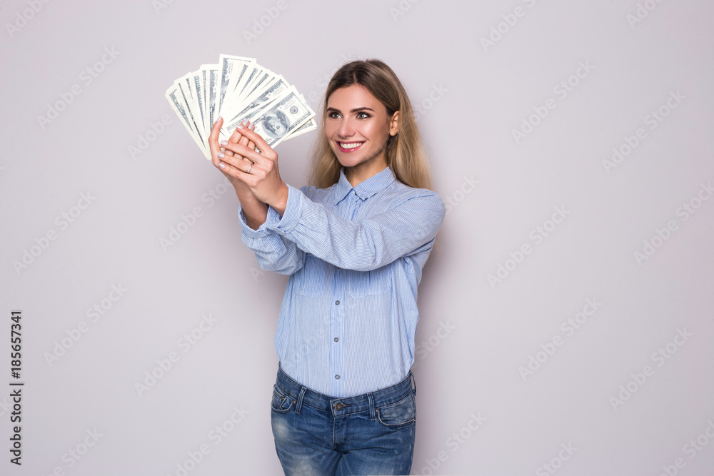 Picture of happy young business woman standing over grey wall holding money. Looking camera. Picture of happy young business woman standing over grey wall holding money. Looking camera.