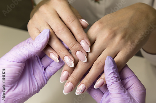 Beauty salon for work with nails manicure. A beauty salon does a manicure to a rich client with black hair.