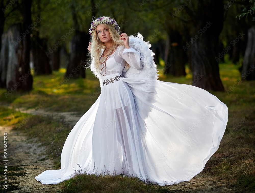 young woman wearing long white dress and angel wings young woman wearing long white dress and angel wings