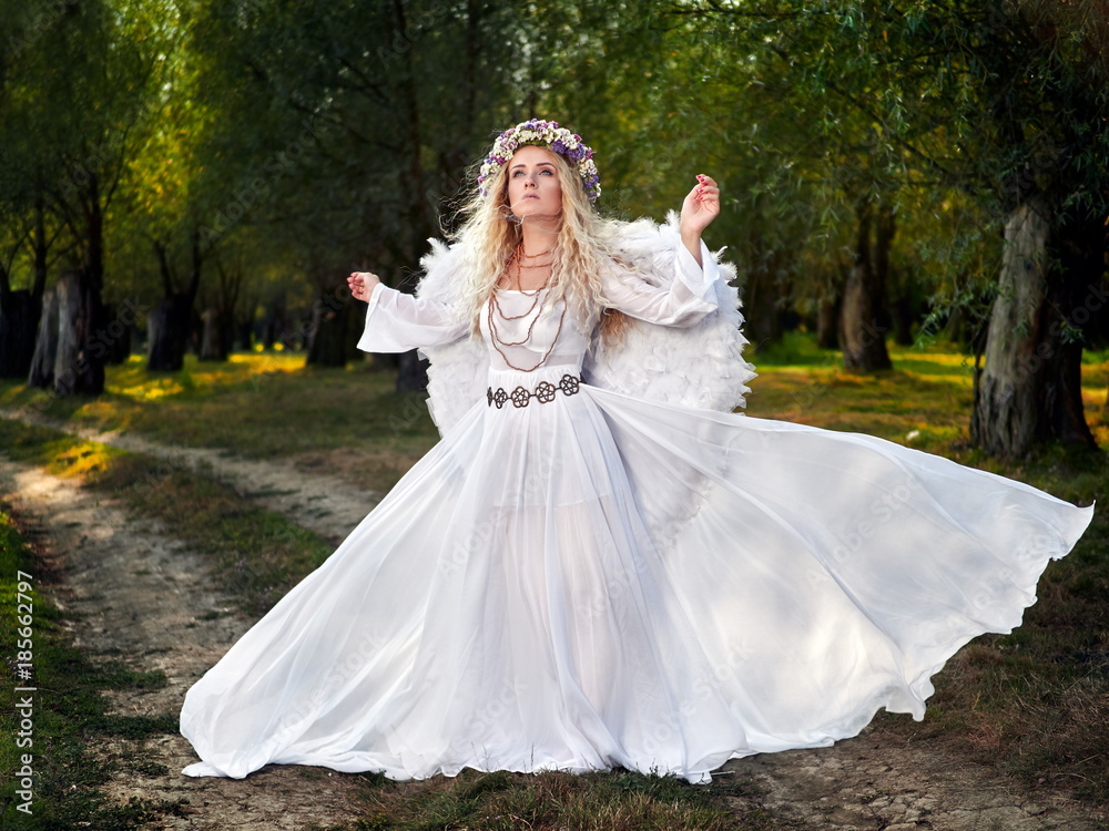 young woman wearing long white dress and angel wings young woman wearing long white dress and angel wings