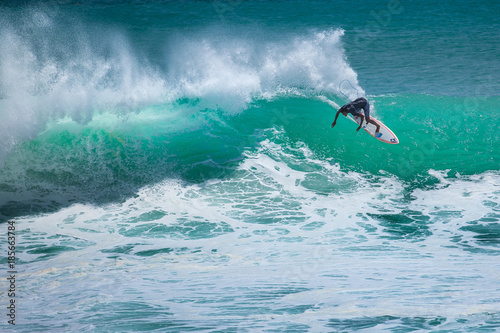 Local surfer riding big wave at Padang Padang beach, Bali, Indonesia