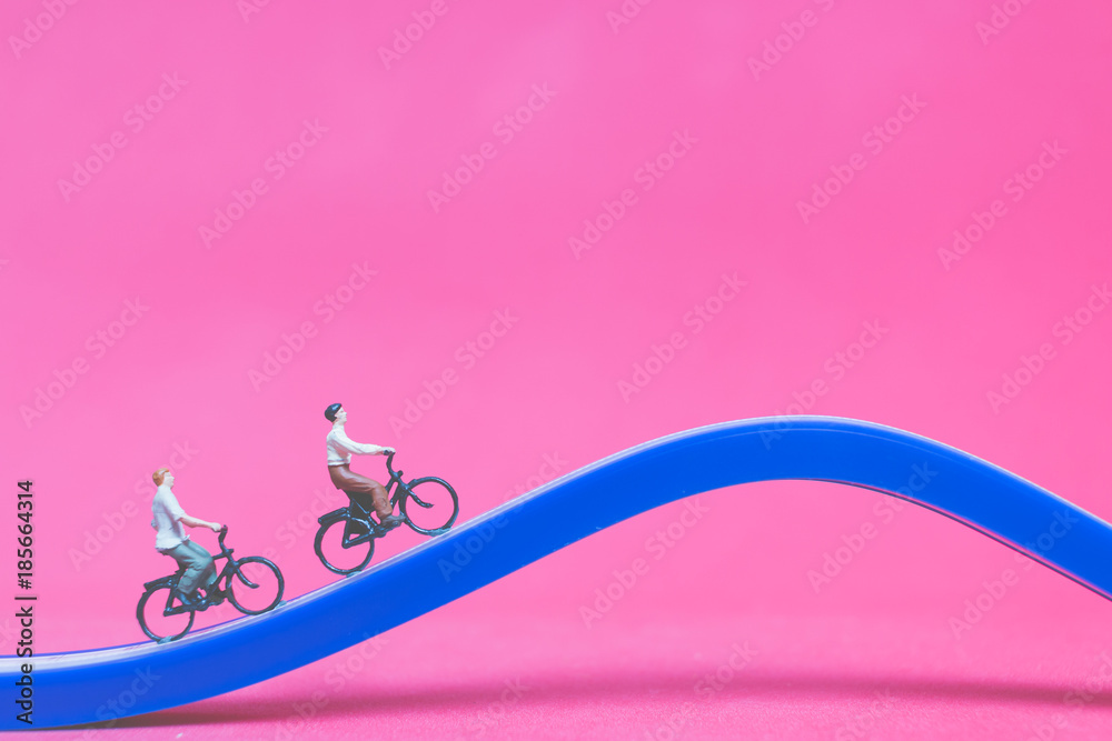 Miniature people travellers with bicycle on The bridge on pink background , Valentine's day concept