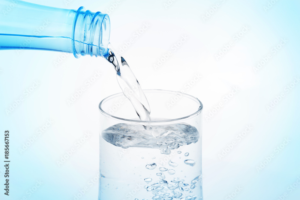 Pouring water from bottle into glass on white background. Pouring water from bottle into glass on white background.