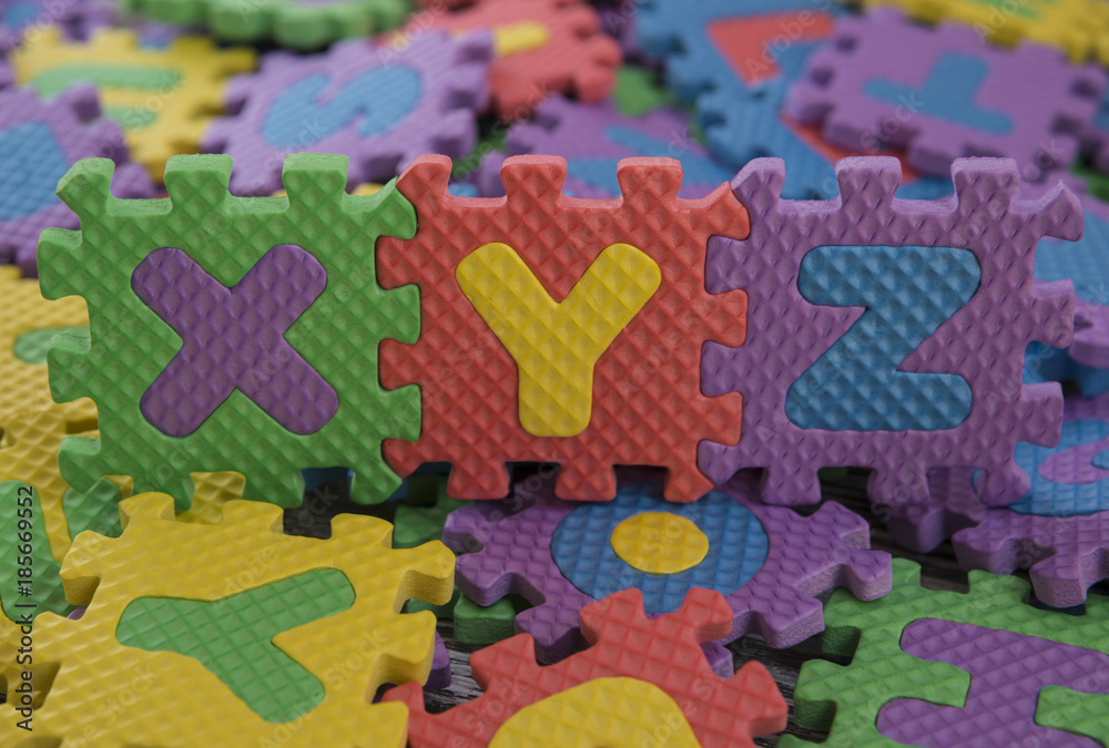 the alphabet children's puzzles. xyz against the background of scattered colored pieces of the puzzle