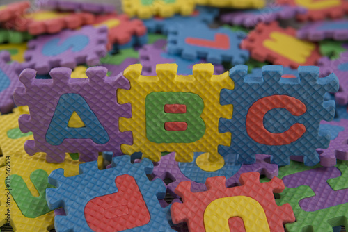 the alphabet children s puzzles. abc against the background of scattered colored pieces of the puzzle