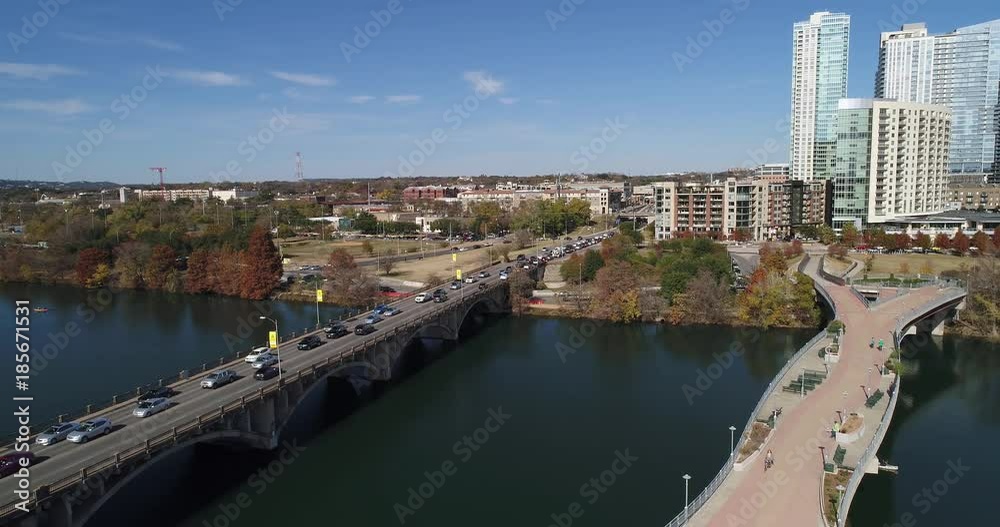 A slow forward aerial establishing shot (DX) of the Austin city skyline with the Pfluger Pedestrian Bridge and Lamar Boulevard Bridge in the foreground on a late sunny Autumn day. A slow forward aerial establishing shot (DX) of the Austin city skyline with the Pfluger Pedestrian Bridge and Lamar Boulevard Bridge in the foreground on a late sunny Autumn day.