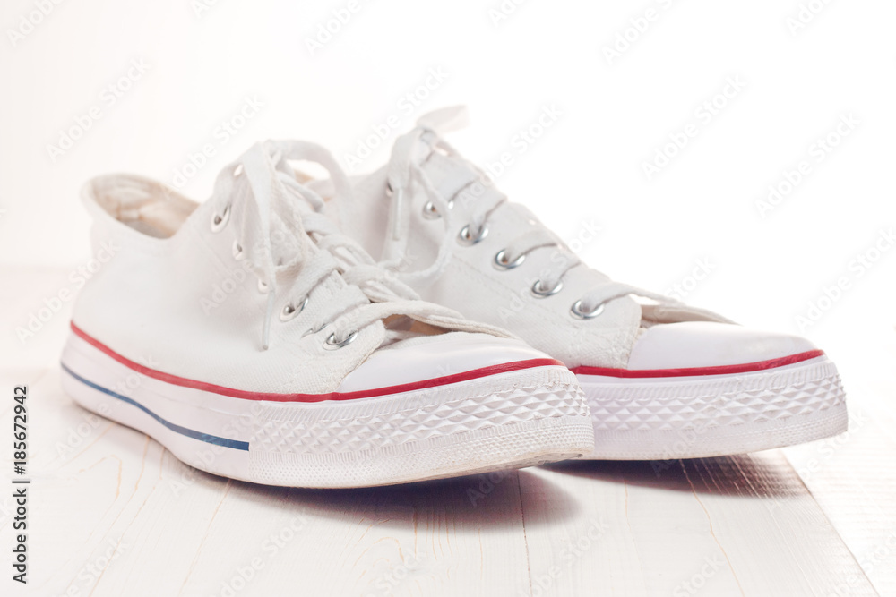 A pair of new white hipster sneakers on a wooden background