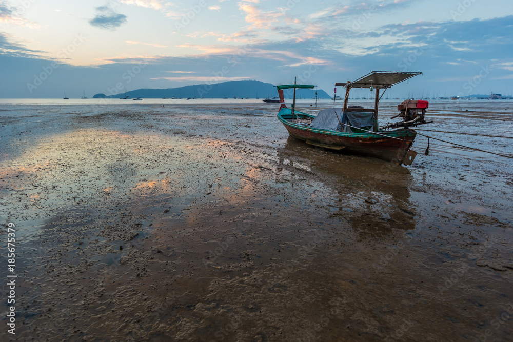 Fishing boat at the beach (long-tail boats) in low water and the beautiful sunrise at Phuket Island, Thailand.