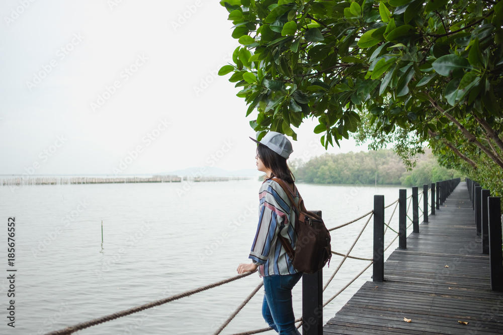 travel background beautiful young women stand alone on bridge with tree and sea. image for nature, scenery, person, portrait, tourist concept