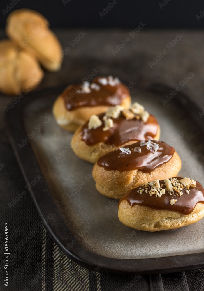 Salted caramel eclairs plated in a dark mood.