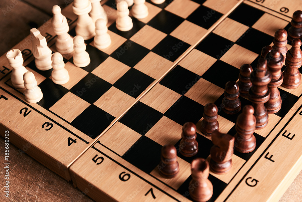 Chess pieces and chessboard on a wooden table Chess pieces and chessboard on a wooden table