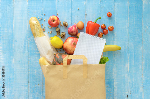 Paper bag different fresh health food notebook on wooden background