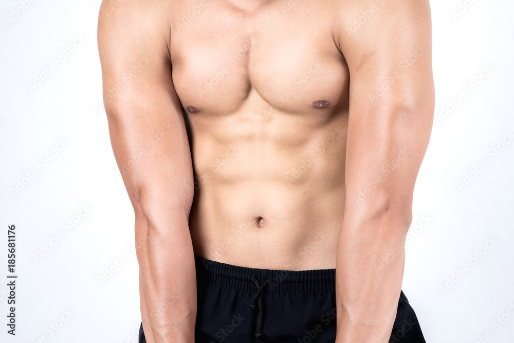 Fitness and health concept. Fit sport man flexing his body showing his six packs, isolated on white background. Half naked Asian chinese lean muscular male wearing a black shorts.