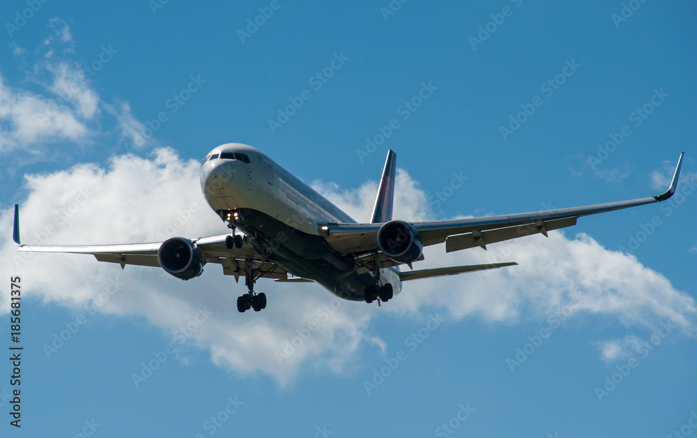 Fototapeta premium Samolot na tle błękitnego nieba i białych chmur.