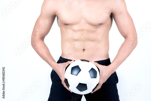 Fitness and health concept. Fit sport man holding a soccer ball, isolated on white background. Half naked Asian chinese lean muscular male wearing a black shorts. © Baan Taksin Studio