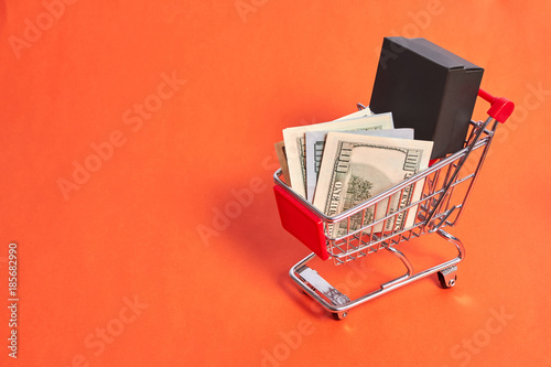 shopping trolley with moneyand gift box on yellow backgroud photo