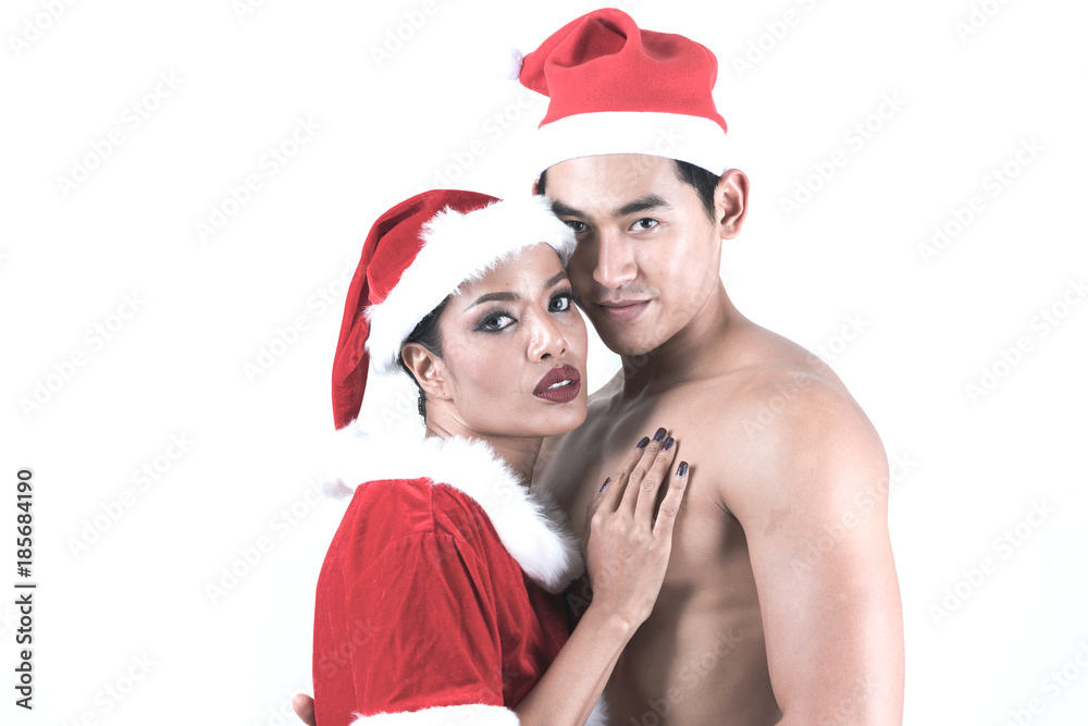 Obraz premium Naked asian man wearing nothing but santa clause hat with sexy asian woman in santa clause dress touching his chest. Isolated on white background, studio shot.