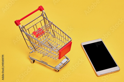 shopping trolley cart with credit card and phone on yellow backgroud