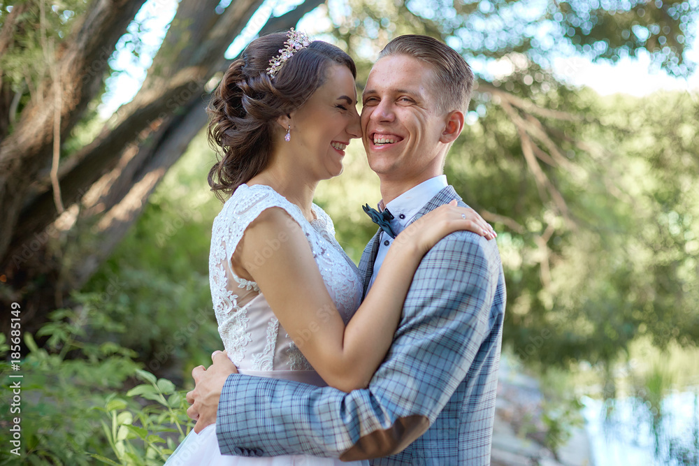 Fototapeta premium The groom holds the bride in her arms near beautiful lake in forest .Wedding couple in love on wedding day