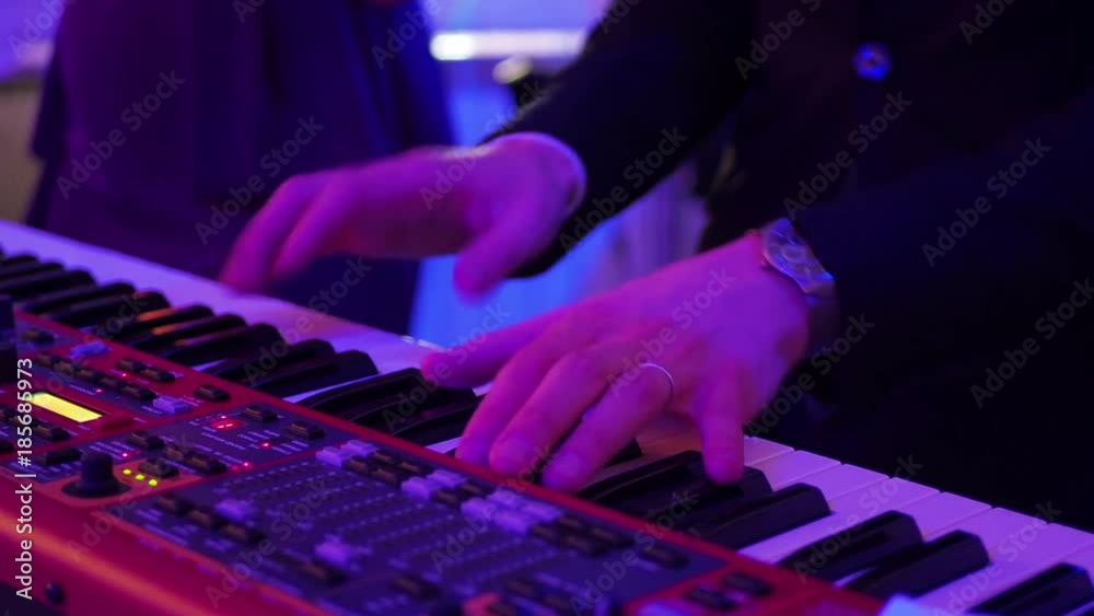 Male hands playing a synth in shallow focus