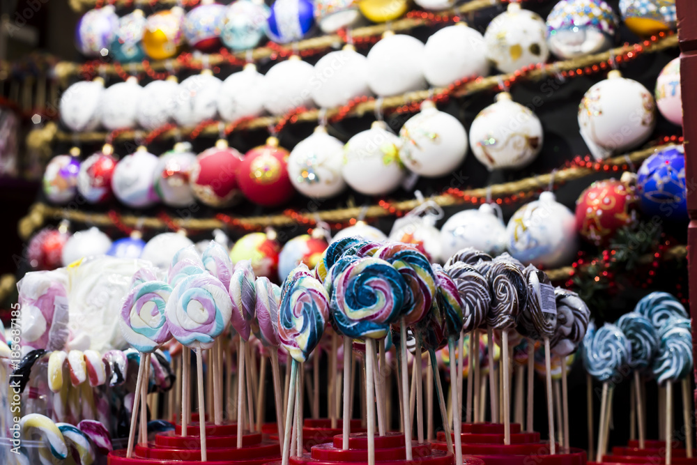 Naklejka premium Sweet candies on the Christmas market counter against the background of Christmas toys