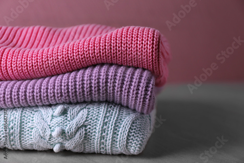Folded knitted sweaters on table. Seasonal female wardrobe