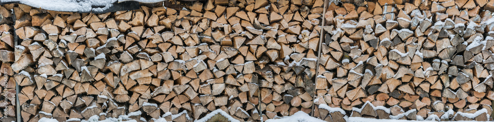 Panorama of snowy firewood as a background or texture