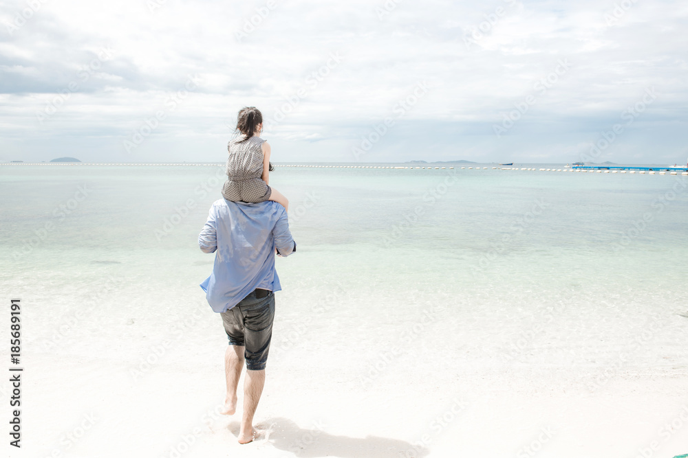 Young family on beach holding each other. Young happy interracial family on beach hugging together. Caucasian man, young girl. Young mixed race family concept.