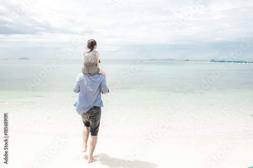 Young family on beach holding each other. Young happy interracial family on beach hugging together. Caucasian man, young girl. Young mixed race family concept. © Baan Taksin Studio