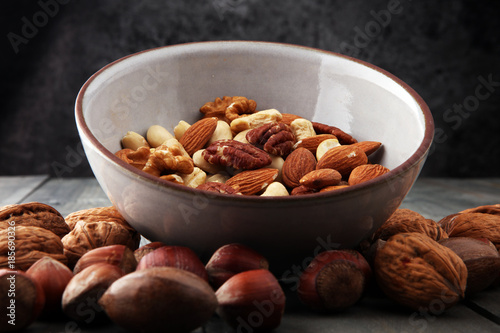 bowl with mixed nuts on wooden background. Healthy food and snack. Walnut, pecan, almonds, hazelnuts and cashews.