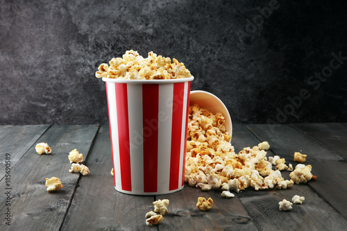 Paper cup in red and white with popcorn on wooden background