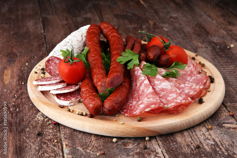Food tray with delicious salami, pieces of sliced ham, sausage, tomatoes, salad and vegetable - Meat platter with selection - Cutting sausage and cured meat Food tray with delicious salami, pieces of sliced ham, sausage, tomatoes, salad and vegetable - Meat platter with selection - Cutting sausage and cured meat
