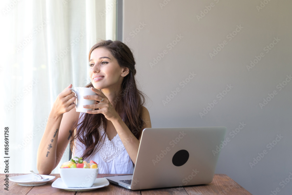 Woman having coffee and working outside. Working on laptop during her vacation in a tropical hotel. White female with white dress. Agile. modile office concept. Woman having coffee and working outside. Working on laptop during her vacation in a tropical hotel. White female with white dress. Agile. modile office concept.