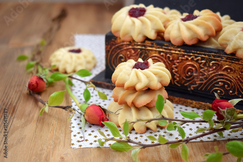 Shortbread cookies with jam on a cloth surrounded by branches and roses