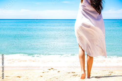 Beautiful young single white woman on beach. Standing happy freedom pose relaxing, wearing white dress.