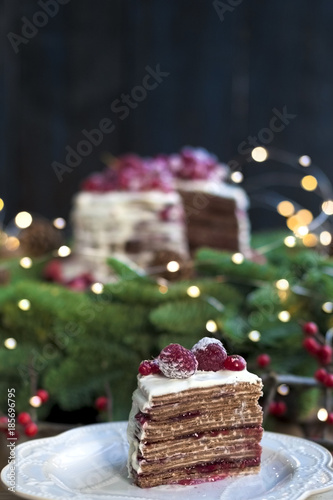 cake with red berries near a Christmas tree on a black background
