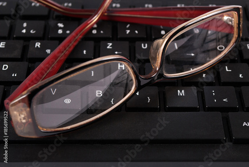 Black computer keyboard and glasses, close up. Selective focus. © Emilija