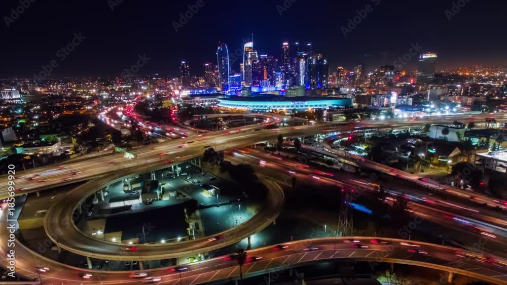Urban aerial timelapse of downtown Los Angeles convention center, skyline and freeways with traffic at night.