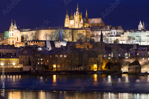 Night colorful snowy Christmas Prague Lesser Town with gothic Castle and Charles Bridge, Czech republic