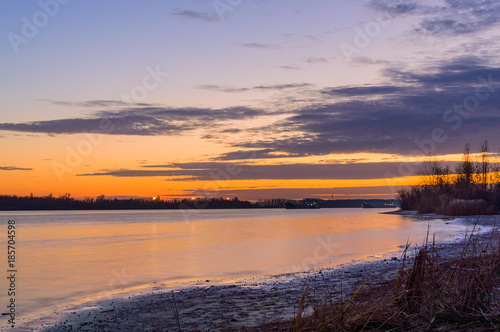 Scenic sky over the river at sunset time. View from the shore