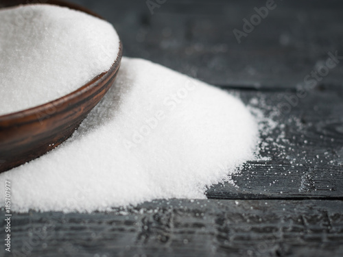 White salt, finely ground poured from a clay bowl on wooden table. photo