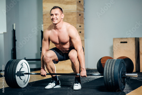 Athlete wearing black shorts lifting big barbell