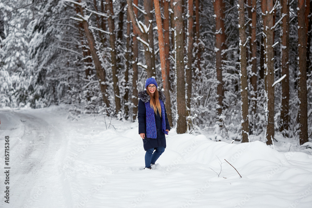girl in blue knitted scarf with hat in winter forest.
