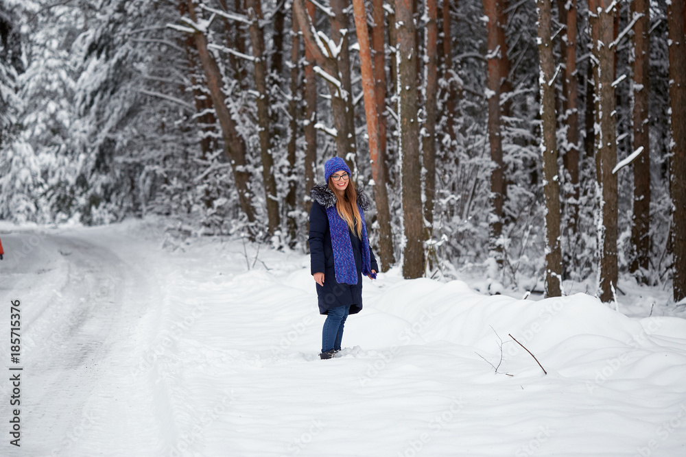 girl in blue knitted scarf with hat in winter forest.