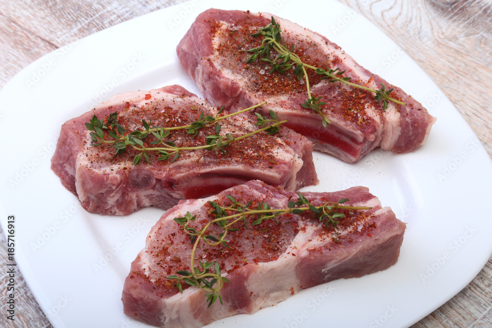 Raw pork chops, spices and rosemary on cutting board. Ready for cooking.