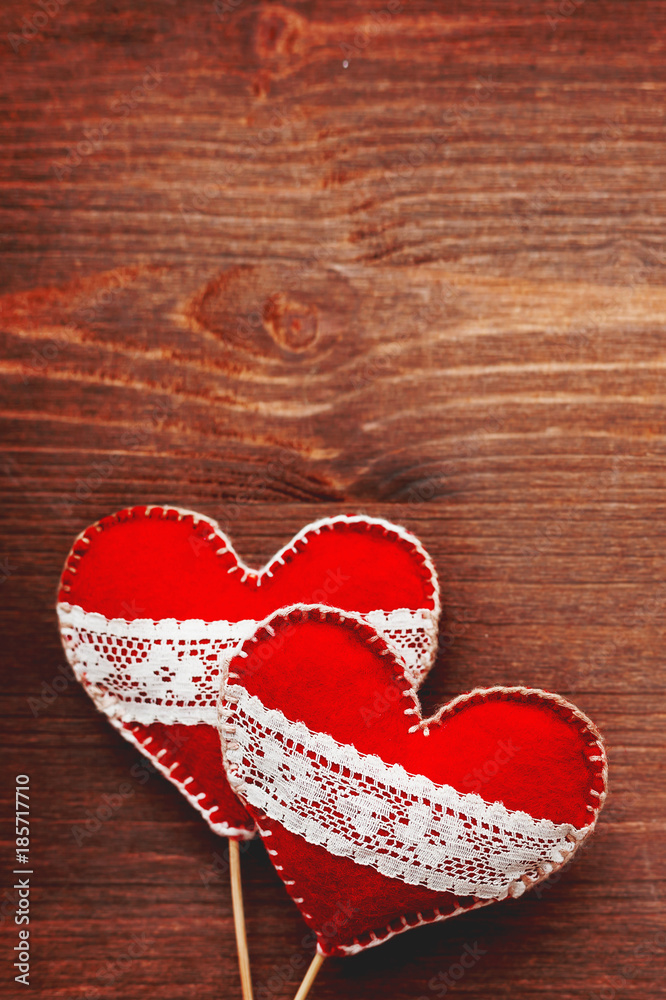 Fototapeta premium Two felt hearts with laces, symbol of love, on wooden background. Good for Valentine's Day cards. Place for text.