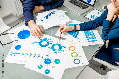 Marketer or analityc manager team working on paper charts at the table. Image focused on the documents photo