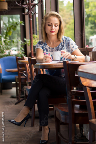 Young Business Woman in the Cafe with a Cup of Coffee and a Phone  © Curasevici