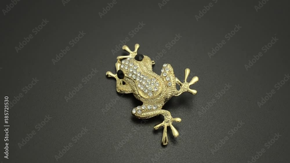 Gold brooch frog with diamonds isolated on black